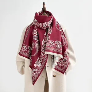 Detail of burgundy paisley scarf with fine fringes on beige wool coat mannequin