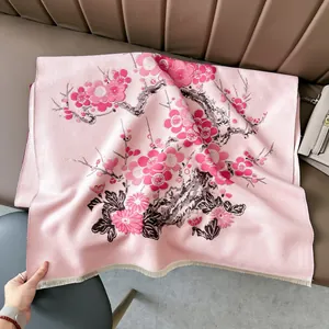 Sciarpa rosa in finto cashmere con fiori di prugno esposta su sedia in pelle