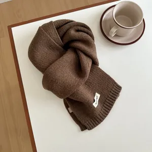 Detail of dark brown knitted wool scarf texture with professional woven brand label