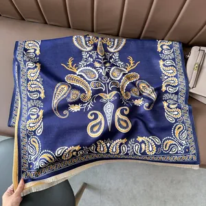 Detailed view of dark blue paisley scarf with tassels against a brown leather surface