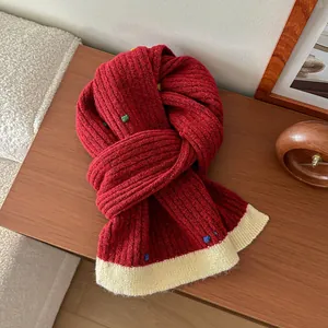 Close-up of thick red knit scarf with colorful specks and cream contrast edge detail