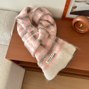 Gros plan sur la texture moelleuse de l'écharpe en laine à carreaux rose et gris