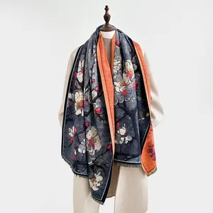 Detail eines floralen Kaschmir-Schals mit blauem Magnolienprint und oranger Rückseite