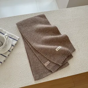 Detail shot of brown knit wool scarf label showing material composition and texture