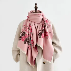 Dettaglio del motivo floreale e consistenza morbida sulla sciarpa rosa effetto cashmere