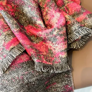 Detalle de bufanda gris y rosa con patrón de pintura al óleo y flecos sobre cuero
