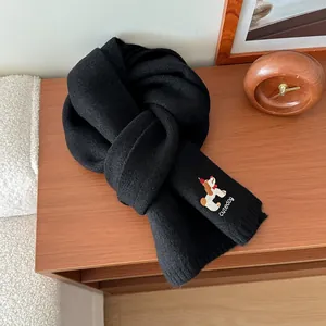Dettaglio di sciarpa in maglia nera con ricamo a forma di cane e scritta cutedog