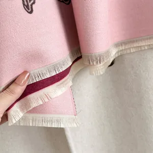 Dettaglio dello scialle pashmina rosa in cashmere con frange bianche e trama a righe