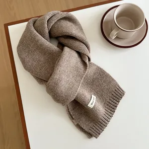 Detail of soft brown knitted wool scarf texture with elegant woven label and ribbed edges