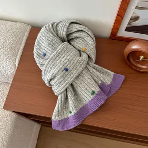 Detail of grey knitted wool scarf with colorful polka dots on a dark wooden table