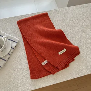 Detailed view of the 70% wool blend fabric and product label on a rust orange scarf