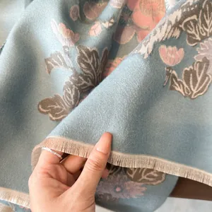 Dettaglio di sciarpa morbida effetto cashmere con motivi floreali e frange sottili