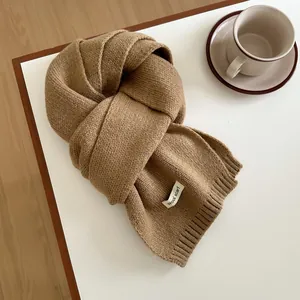 Detail of camel wool scarf with textured knit finish and white fabric label