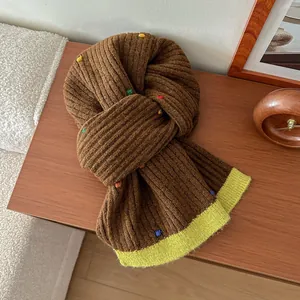 Detail of brown wool knitted scarf with colorful 3D dots and bright neon yellow hem