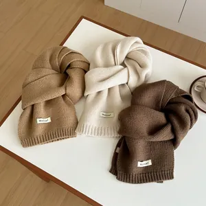 Detailed close-up of premium wool scarves in camel and beige with woven brand labels