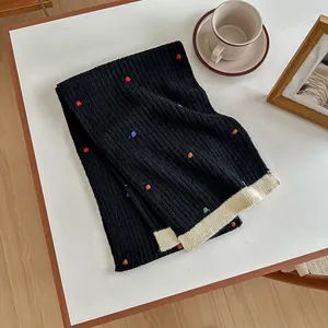Detail of black knitted wool scarf with colorful polka dots and cream ribbed edge