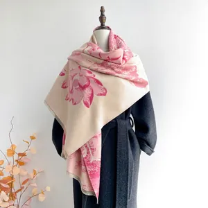 Gros plan d'une écharpe beige au motif floral rose avec des détails de franges