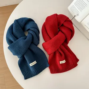 Close-up of wool knit scarves in navy and red featuring a premium stitched label