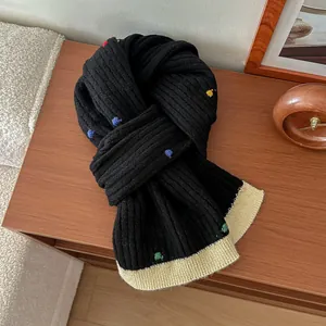 Detailed macro view of black chunky knit scarf with colorful dots and beige ribbed trim