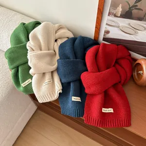 Detailed knit texture of wool scarves in green, white, blue and red with woven labels