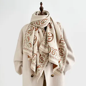 Close-up of paisley pattern on winter thick beige scarf with fringe on a mannequin