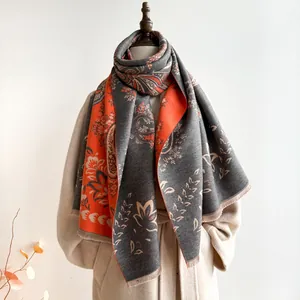 Detail of bohemian paisley jacquard scarf with orange and grey floral patterns and fringe
