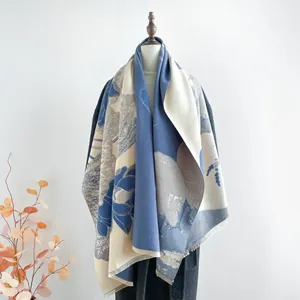 Détail d'une écharpe en cachemire bleu avec motif floral et bordures à franges douces