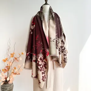 Detail of floral jacquard scarf with tassels draped over a coat for a layered look