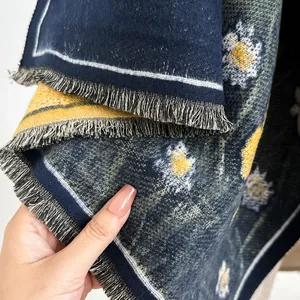 Close-up of winter shawl showing navy blue knit texture, daisy pattern and fringe trim