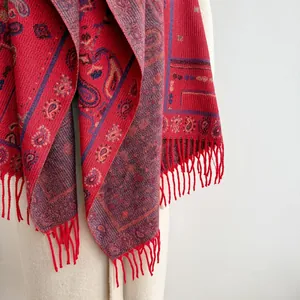 Detailed texture of red bohemian paisley shawl with fringe trim and ethnic jacquard weaving