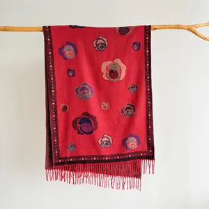 Detailed texture of red cashmere-feel shawl with vintage floral patterns and tassels
