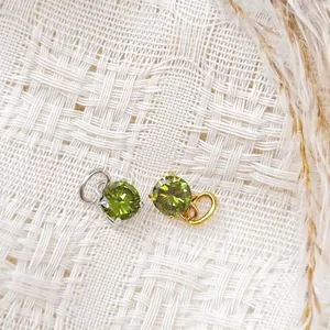 Detailed macro of gold and silver plated pendants with round faceted olive green gems