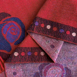 Macro shot of red pashmina shawl featuring intricate floral jacquard and woven borders
