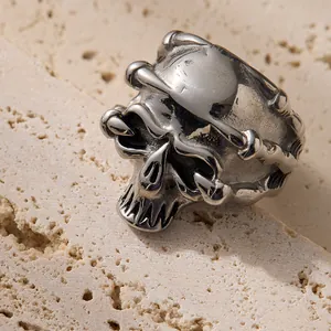 Vintage silver skull ring with gothic bone band detail on textured stone surface