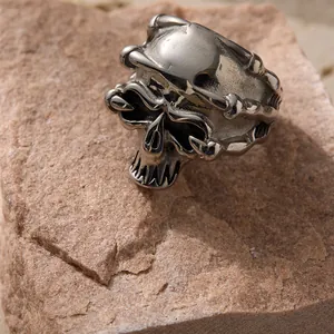 Punk style skull ring for men in vintage silver finish displayed on a natural rock