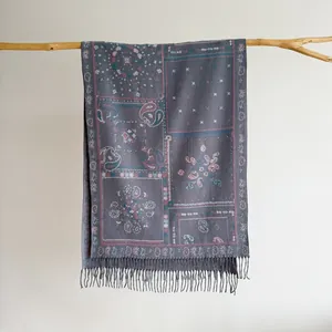 Detail of bohemian paisley jacquard shawl with tassel fringe on a wooden branch