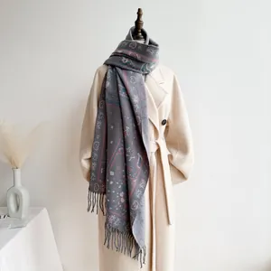 Detail of bohemian paisley print scarf with fringe, layered on a wool coat