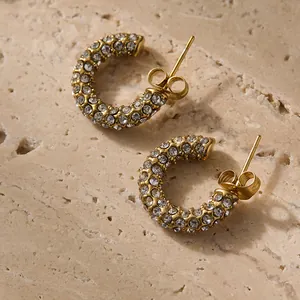 Vue macro de boucles d'oreilles en C plaquées or serties de zircons avec fermoir papillon