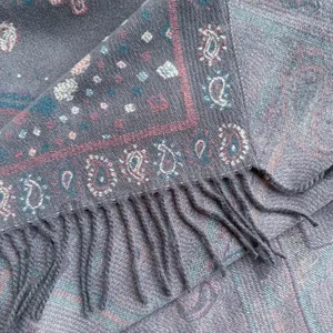Macro shot of paisley jacquard pattern with fringe detail on blue bohemian shawl