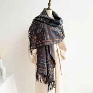 Detail of bohemian paisley jacquard shawl with black fringe on a beige coat display