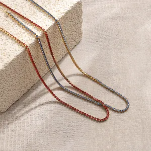 Détail rapproché de colliers dorés avec zircons rouges et bleus sur support pierre