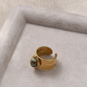 Macro view of wide 18K gold plated ring with wheat pattern and oval gemstone inlay