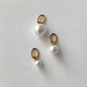Three elegant freshwater pearl pendants in various sizes with gold metal loops on white