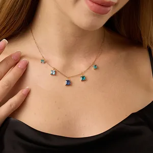 Gold chain necklace with five square-cut blue gradient gemstone pendants on a model