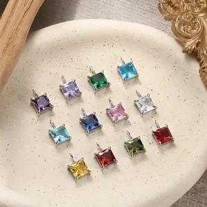 Detailed close-up of square colorful zircon pendants with silver prong settings in a tray