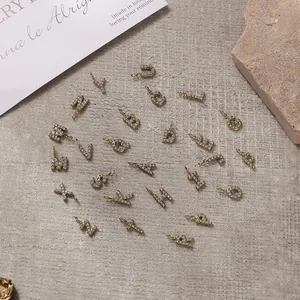 Golden A-Z alphabet pendant set with sparkling rhinestones on a textured background