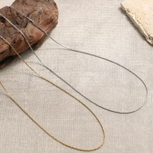 Eleganti collane a catena sottile in oro e argento su sfondo materico naturale