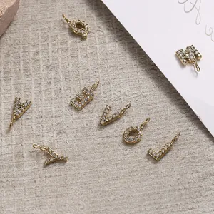Close-up of gold plated rhinestone letter pendants on beige textured background