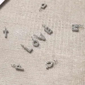 Macro detail of silver letter pendants with white zircon stones for DIY jewelry