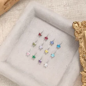 Detail of thirteen colorful star-shaped gemstone pendants arranged on a jewelry tray